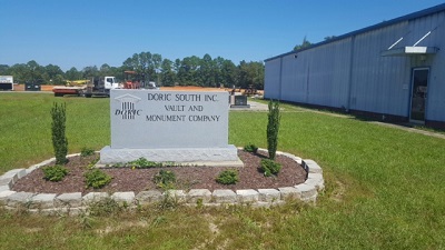 The engraved granite sign at the entrance to the Doric South yard in Moss Point, Mississippi, reading Doric South Inc. Vault and Monument Company